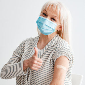 Senior woman with facemask giving thumbs up sign