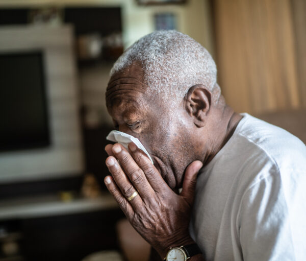 Senior man blowing his nose at home